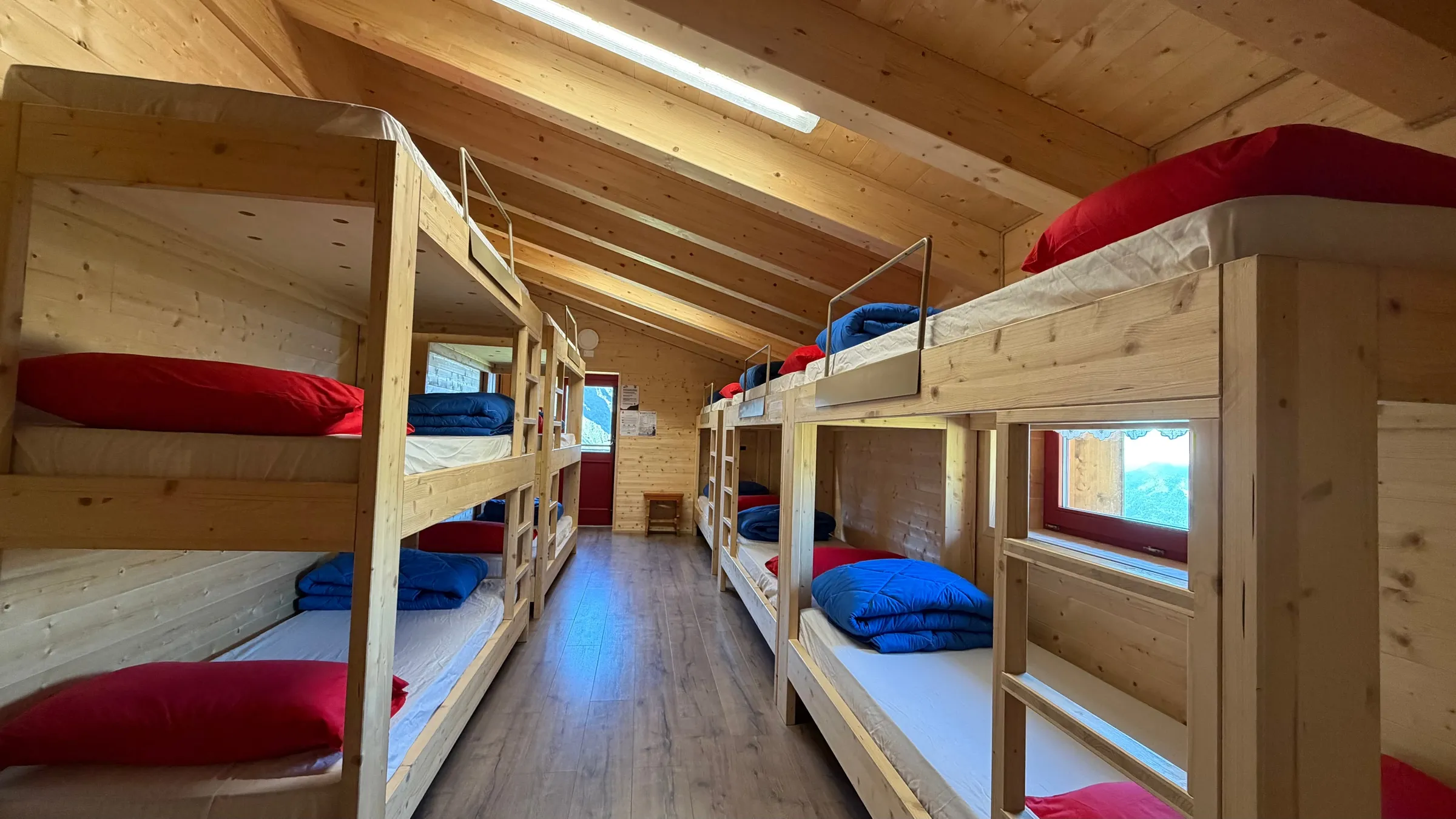 Camerata con letti a castello in legno e vista sulle vette